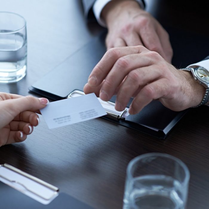 Hand of woman giving business card to businessman